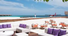 Beach bar with white chairs next to the water