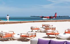 Beach bar with white chairs next to the water